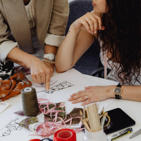 Two people are looking at each other discussing fashion design via Canva